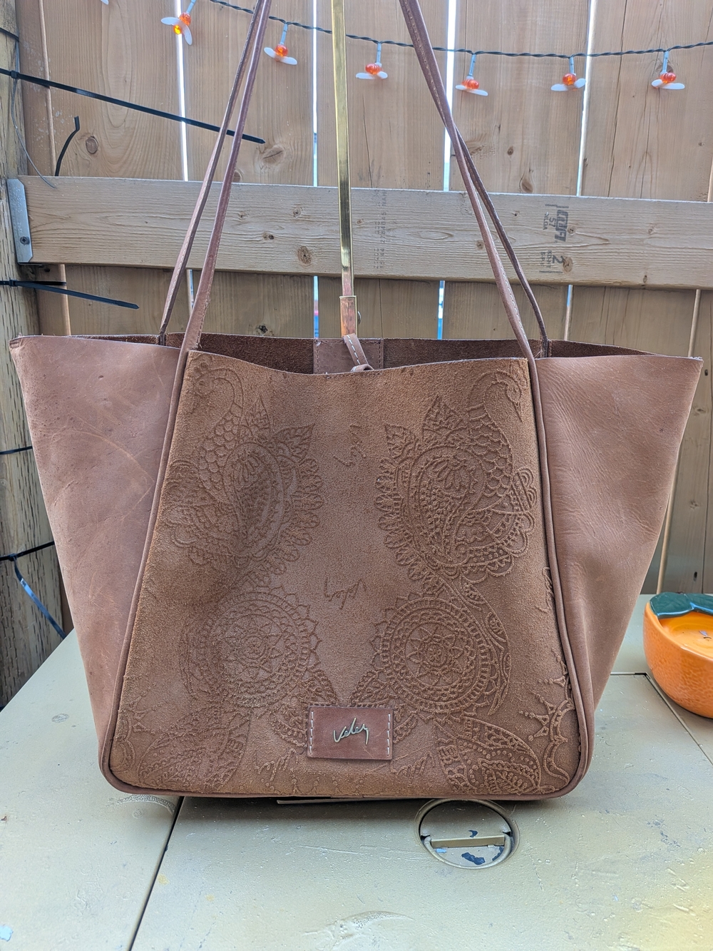 Vélez leather tote features a distinct embossed paisley and floral design across